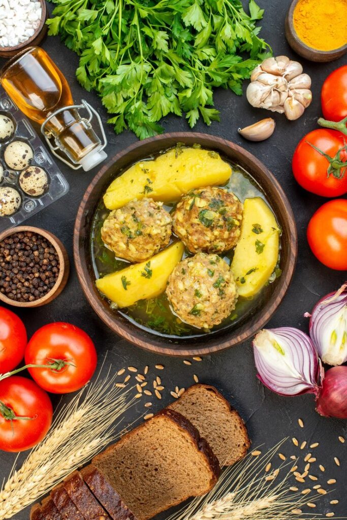 Manishkumar-Patel-Pelham-Manor-westchester-overhead-view-black-bread-slices-delicious-meatballs-meal-with-potatoes-green-fresh-vegetables-black-background_140725-159875